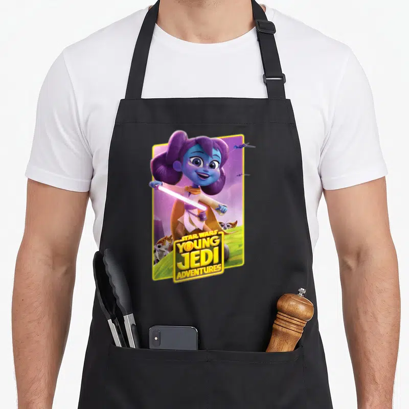 Tablier de cuisine noir avec une illustration colorée de Lys Solay tenant un sabre laser rose sur fond violet et vert.