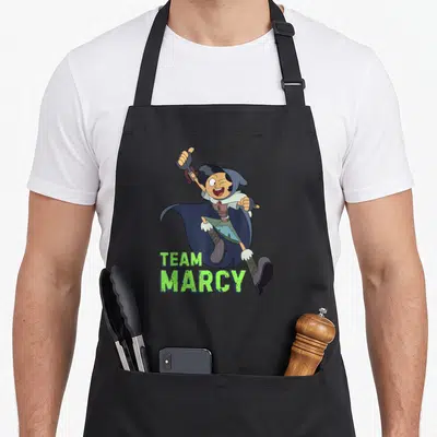 Tablier de cuisine noir avec une illustration d'une sorcière sautant et le texte Team Marcy en vert.