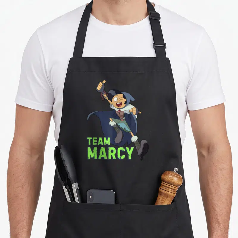 Tablier de cuisine noir avec une illustration d'une sorcière sautant et le texte Team Marcy en vert.