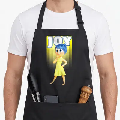 Tablier de cuisine noir avec le portrait de Joy aux cheveux bleus et une robe jaune sous le mot JOY.
