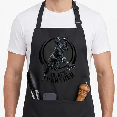 Tablier de cuisine noir avec illustration Black Panther en mouvement et texte imprimé en bas.