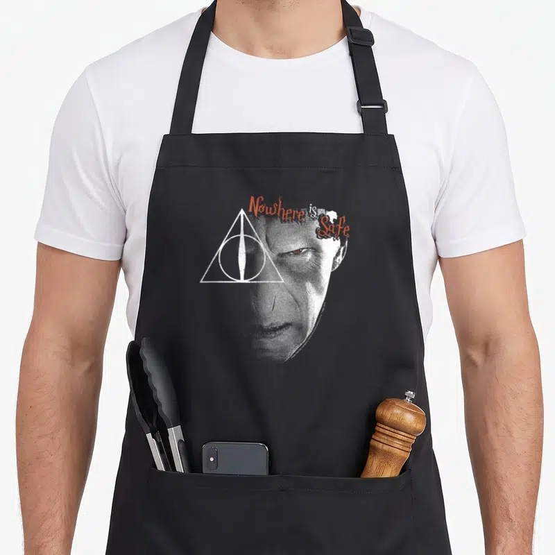 Tablier de cuisine noir avec portrait stylisé de Voldemort et le symbole des Reliques de la Mort en blanc et rouge.