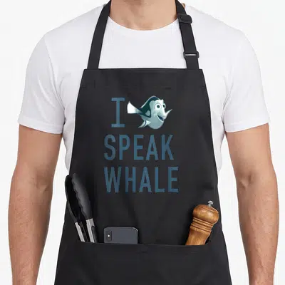Tablier de cuisine noir avec le visage de Dory et le texte I SPEAK WHALE en bleu.