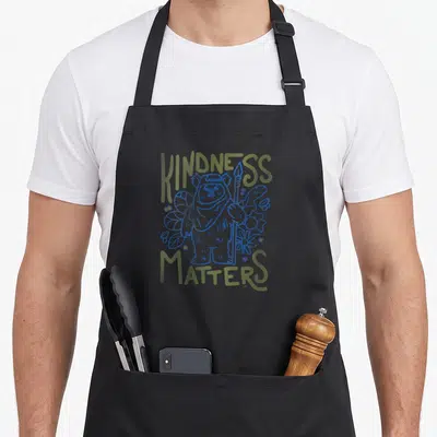 Tablier de cuisine noir avec illustration bleue d'Ewok entouré de fleurs et texte vert Kindness Matters.