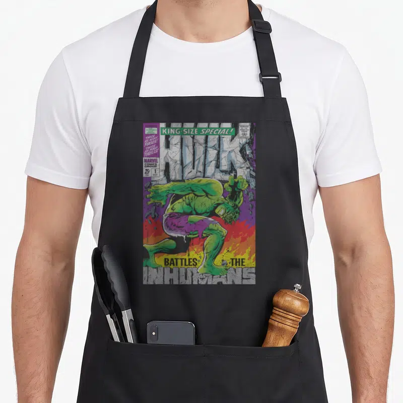 Tablier de cuisine noir avec une illustration colorée du Hulk vert en pleine action sur fond de comics anciens.