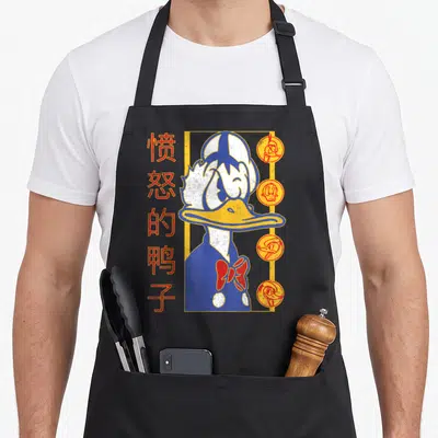 Tablier de cuisine noir avec illustration stylisée de Donald Duck et caractères Kanji rouges sur le côté gauche.