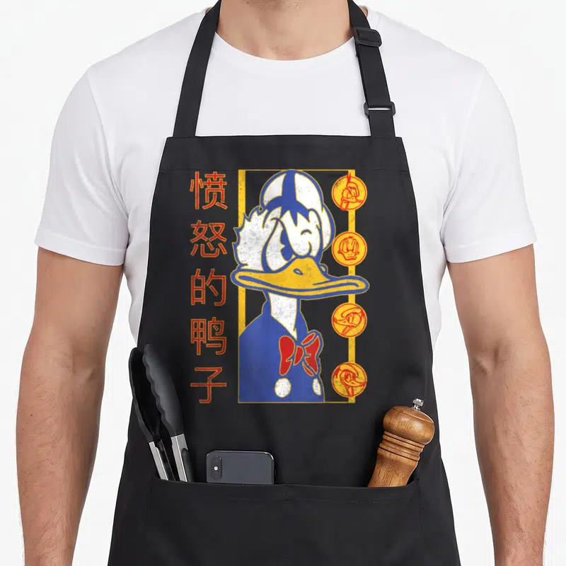 Tablier de cuisine noir avec illustration stylisée de Donald Duck et caractères Kanji rouges sur le côté gauche.