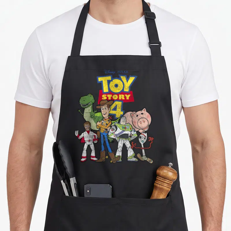 Tablier de cuisine noir avec illustration colorée des personnages de Toy Story 4 et le titre du film en lettres jaunes et rouges.
