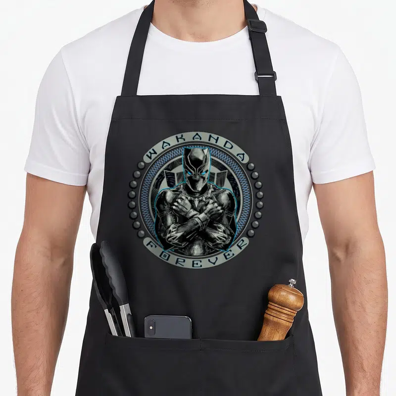 Tablier de cuisine noir avec illustration Black Panther et texte Wakanda Forever entouré de perles.