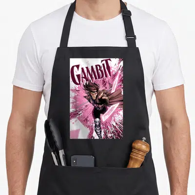 Tablier de cuisine noir avec illustration Gambit et cartes roses explosives sur fond blanc.