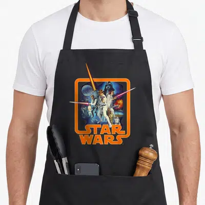 Tablier de cuisine noir avec illustration rétro Star Wars A New Hope et logo orange.