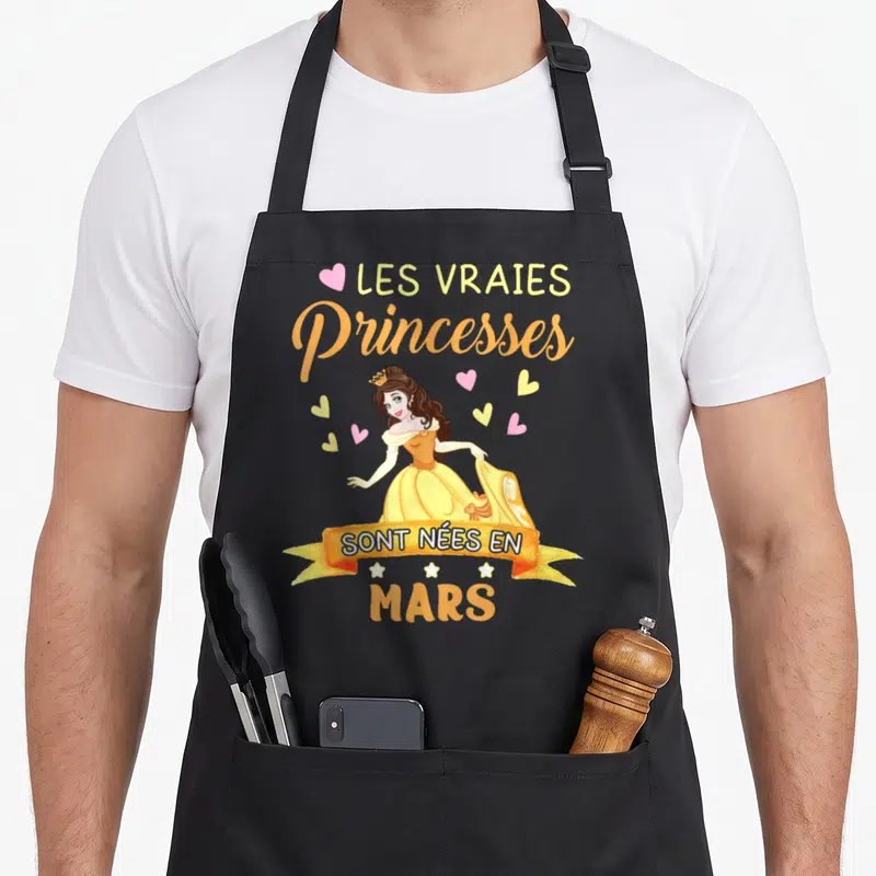 Tablier de cuisine noir avec princesse Belle en robe jaune et texte Les vraies princesses sont nées en mars entouré de cœurs.