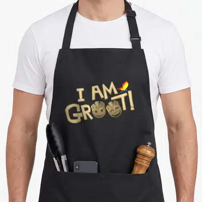 Tablier de cuisine noir avec le texte I AM GROOT et deux visages mignons de Groot accompagnés d'un papillon coloré.