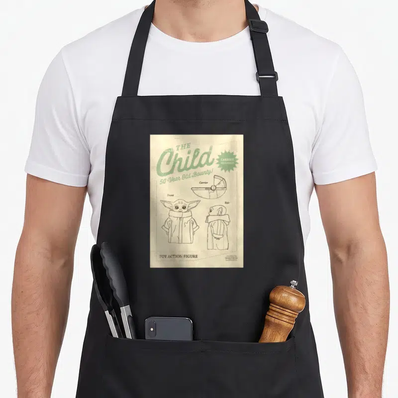 Tablier de cuisine noir avec schéma vintage du Child et texte 50 Year Old Bounty en vert sur fond beige vieilli.