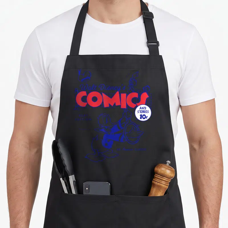Tablier de cuisine noir avec illustration vintage de Donald Duck et le titre Walt Disney's Comics en rouge et bleu.