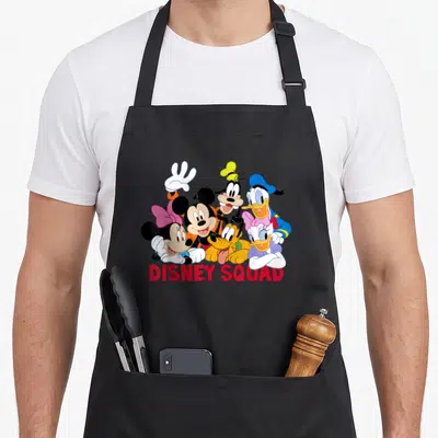 Tablier de cuisine noir avec illustration colorée de Mickey, Minnie, Donald, Daisy, Goofy et Pluto sous le texte DISNEY SQUAD en rouge.