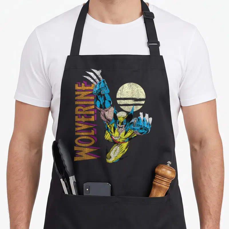 Tablier de cuisine noir avec illustration rétro Wolverine Claws Out et texte vertical orange et violet.