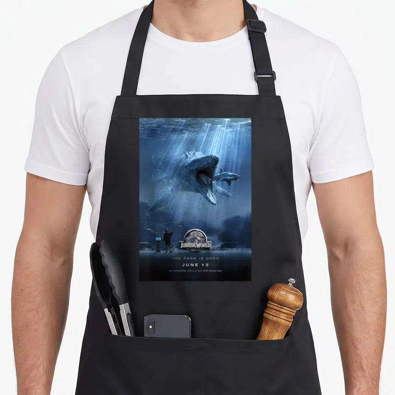 Tablier de cuisine noir avec affiche du Mosasaurus Jurassic World et silhouette observateur