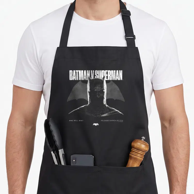 Tablier de cuisine noir avec illustration du cowl de Batman et le texte Batman v Superman en blanc.