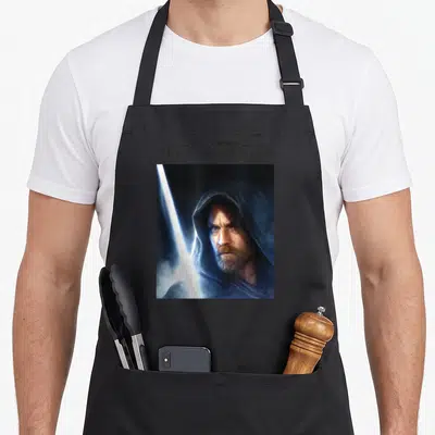 Tablier de cuisine noir avec le portrait d'Obi-Wan Kenobi et un sabre laser lumineux.