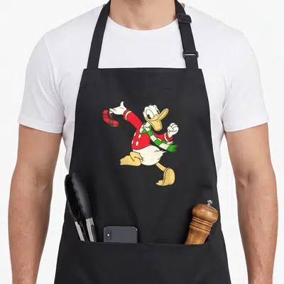 Tablier de cuisine noir avec illustration colorée de Donald Duck en tenue hivernale festive sur le devant.