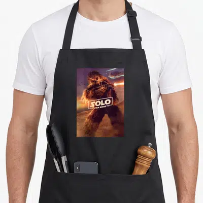 Tablier de cuisine noir avec une illustration de Chewbacca tenant un blaster devant le logo Solo Star Wars Stories.