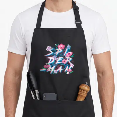 Tablier de cuisine noir avec le texte Spider-Man entrelacé de fleurs roses et de feuilles vertes tropicales.