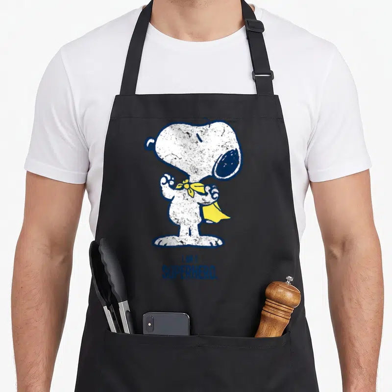 Tablier de cuisine noir avec Snoopy super-héros jaune et texte I am a superhero imprimé en bleu vintage.