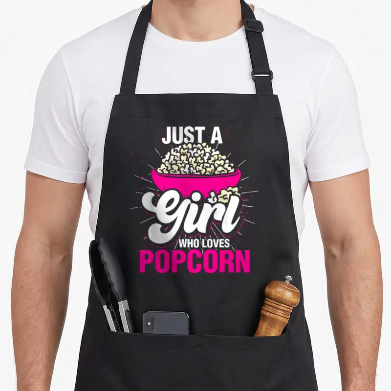 Tablier de cuisine noir avec illustration d'un bol de popcorn rose et texte blanc stylisé.