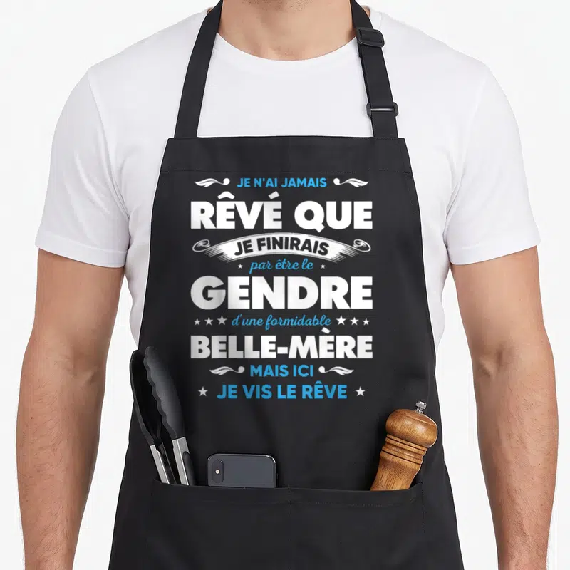 Tablier de cuisine noir avec une inscription humoristique en blanc et bleu célébrant le rôle de gendre heureux auprès d'une belle-mère formidable.