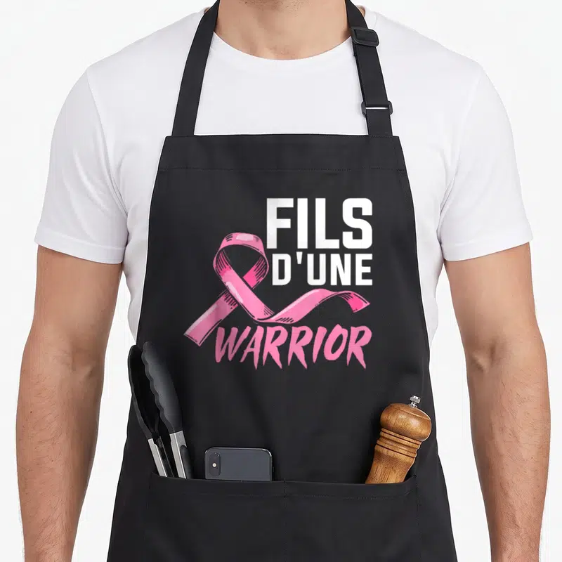 Tablier de cuisine noir avec un ruban rose et l'inscription Fils D'une Warrior en blanc et rose.