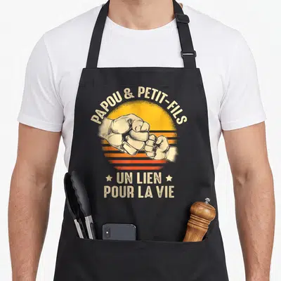 Tablier de cuisine noir avec illustration de deux poings se touchant et texte Papou et Petit-Fils Un lien pour la vie.