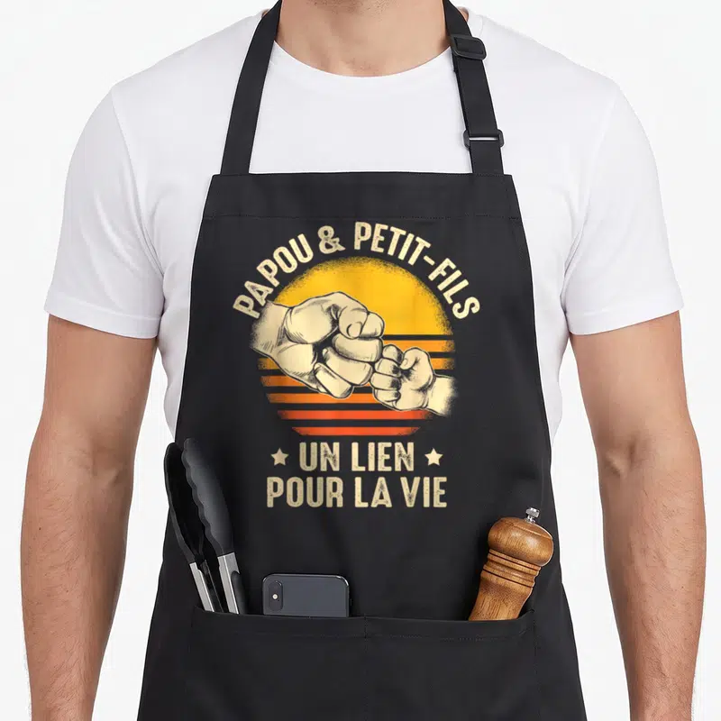 Tablier de cuisine noir avec illustration de deux poings se touchant et texte Papou et Petit-Fils Un lien pour la vie.
