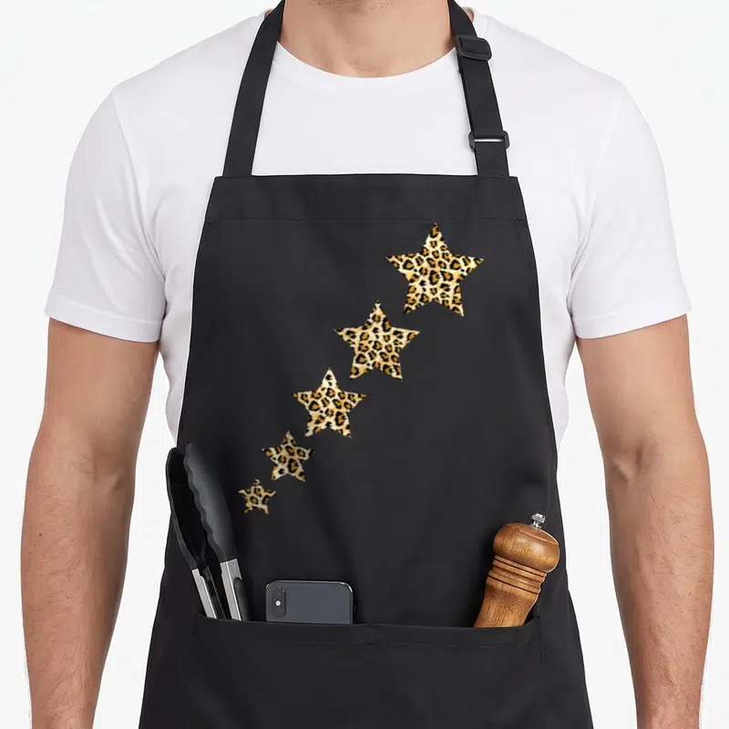 Tablier de cuisine noir avec cinq étoiles de tailles décroantes imprimées en motif léopard guépard.