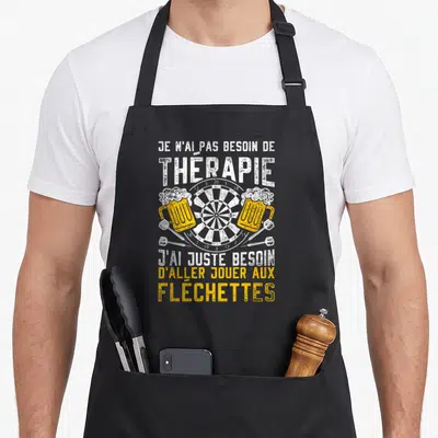 Tablier de cuisine noir avec une cible de fléchettes, deux bières et texte humoristique en blanc et jaune.
