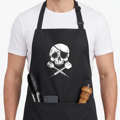 Tablier de cuisine noir avec un crâne de pirate et deux fléchettes croisées en dessin blanc.