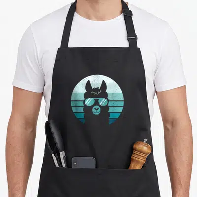 Tablier de cuisine noir avec illustration d'un lama portant des lunettes de soleil sur un cercle bleu strié.
