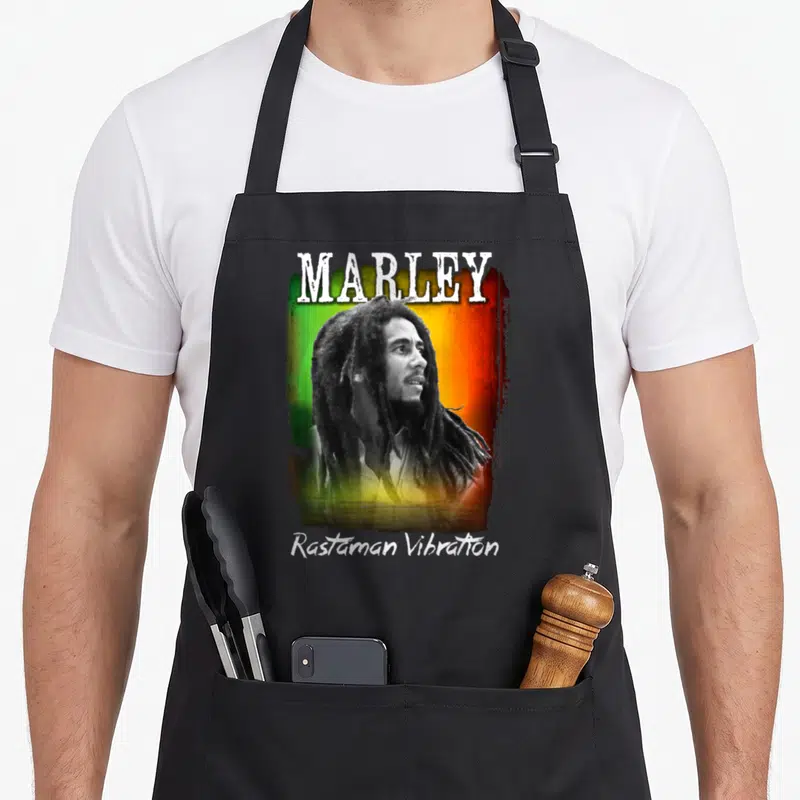 Tablier de cuisine noir avec portrait de Bob Marley sur fond vert jaune rouge et texte Marley Rastaman Vibration