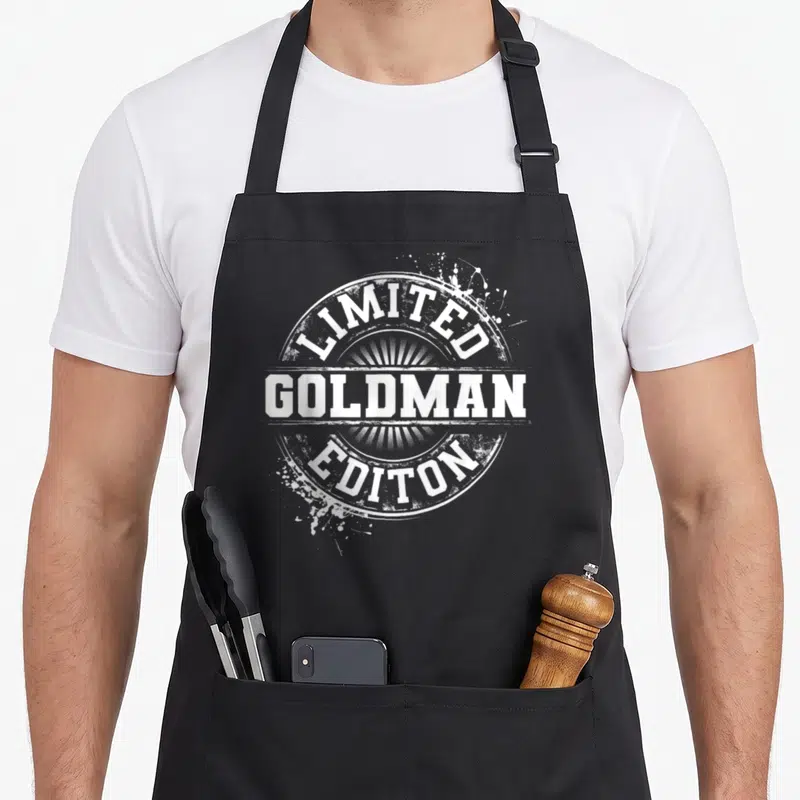 Tablier de cuisine noir avec logo circulaire blanc Limited Goldman Editon et effet éclaboussure.