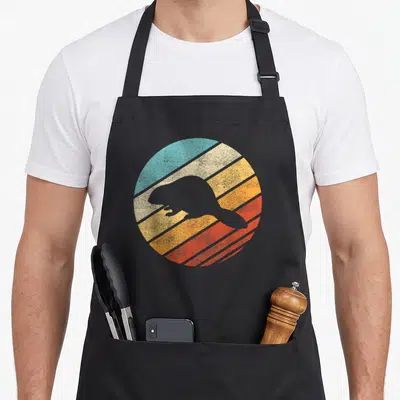 Tablier de cuisine noir avec silhouette de castor sur fond de coucher de soleil rayé aux couleurs pastel et texture vieillie.
