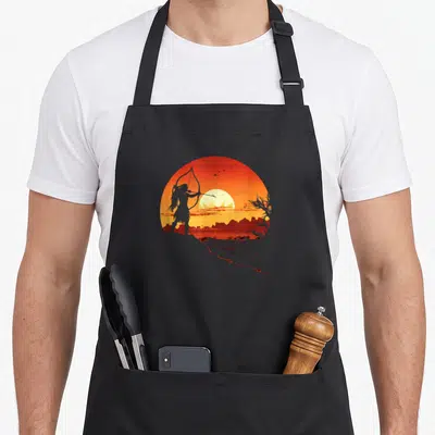 Tablier de cuisine noir avec silhouette d'un guerrier indien et coucher de soleil orange dans un cercle.