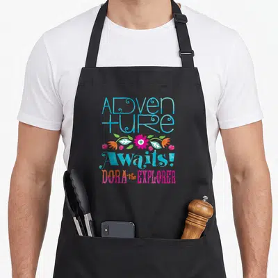 Tablier de cuisine noir avec inscription Adventure Awaits Dora the Explorer et motifs floraux colorés.