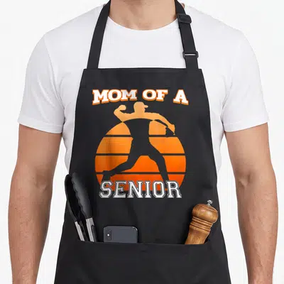 Tablier de cuisine noir avec silhouette orange d'un lanceur de baseball sur fond de soleil rayé.