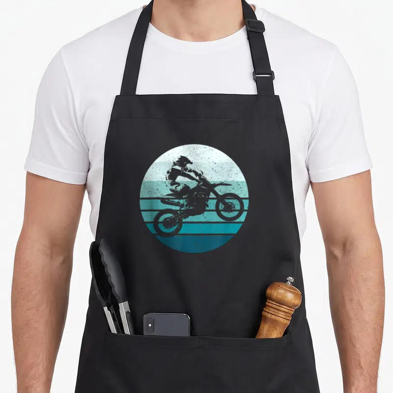 Tablier de cuisine noir avec motif circulaire représentant un motard sur fond de rayures turquoise évoquant un coucher de soleil vintage.
