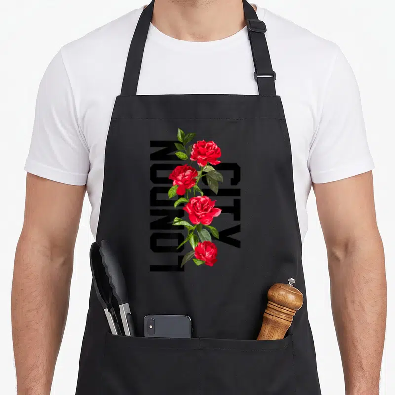 Tablier de cuisine noir avec roses rouges et texte LONDON CITY vertical imprimé au centre.