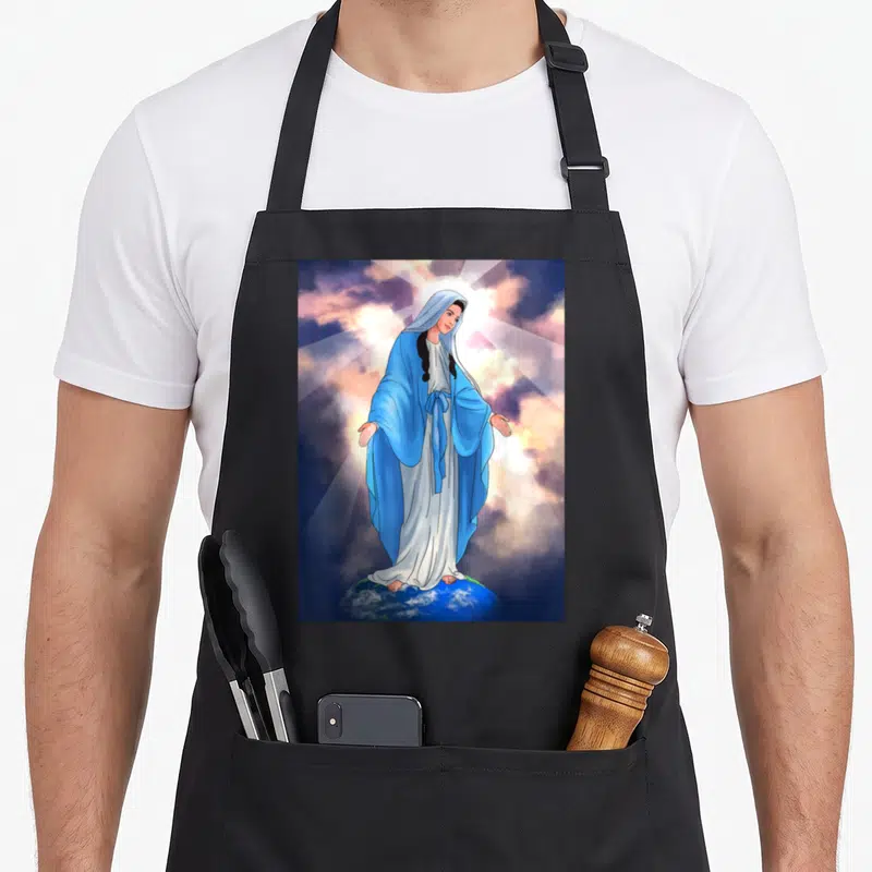 Tablier de cuisine noir avec une illustration de la Vierge Marie debout sur la terre sous des rayons lumineux.
