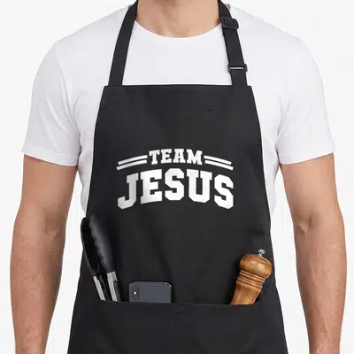 Tablier de cuisine noir avec l'inscription Team Jesus en lettres blanches style sportif et deux lignes décoratives au-dessus du texte.