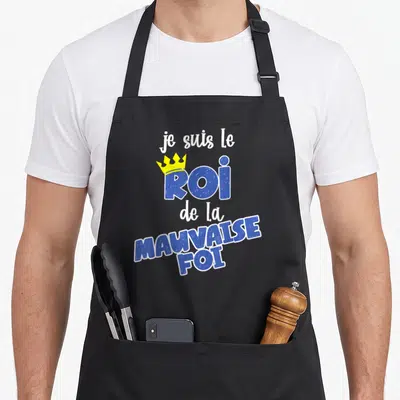 Tablier de cuisine noir avec l'inscription je suis le roi de la mauvaise foi et une couronne jaune sur fond gris uni.