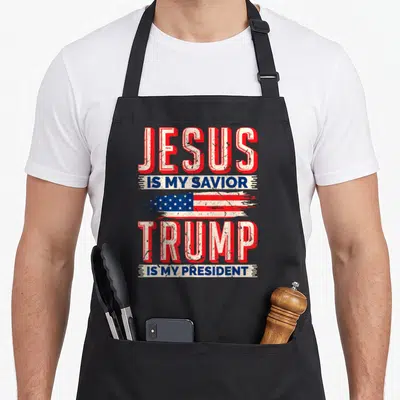 Tablier de cuisine noir avec inscription rouge et bleue JESUS IS MY SAVIOR TRUMP IS MY PRESIDENT 2024 sur fond gris uni.