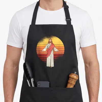 Tablier de cuisine noir avec illustration de Jésus Christ Le Messie sur fond de soleil orange et jaune rayé.